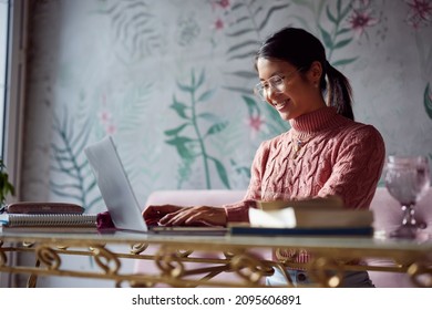 A dedicated student on student exchange is sitting in a coffee shop and typing on her laptop. Student exchange. - Shutterstock ID 2095606891