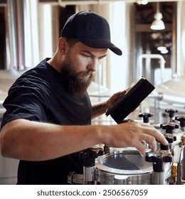 Dedicated technologist checking the brewing process, and equipment quality, maintaining perfect and well-equipped production. Concept of beer, brewery, manufacture, quality control - Powered by Shutterstock