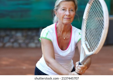 Dedicated tennis player. Senior woman preparing to return a serve during a game of tennis. - Powered by Shutterstock