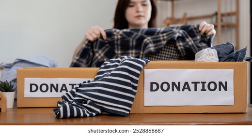 Dedicated Volunteer Organizing Clothing Donations Concept of Philanthropic Action and Social Welfare - Powered by Shutterstock