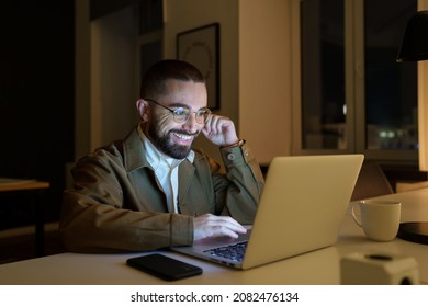 Dedicated Young Specialist Stay At Work Late Busy With New Interesting Project. Happy Pr Manager Or Journalist Read Email Response From Partner Or Customer With Positive Review. Workaholic Man Concept