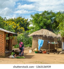 Dedza, Malawi - 03 06 2017: Women Carrying Babies Greet Each Other In Malawian Village