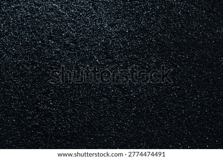 A deep black, textured background with subtle blue glitter accents and a rough, painted surface