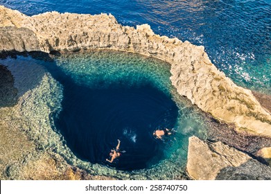 Deep blue hole at the world famous Azure Window in Gozo island - Mediterranean nature wonder in the beautiful Malta - Unrecognizable touristic scuba divers swimming to adventure water cave