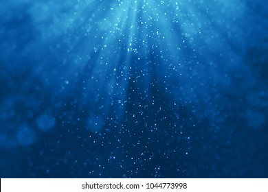 deep blue ocean waves from underwater background with particles flowing movement, light rays shining through - Shutterstock ID 1044773998