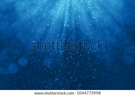 deep blue ocean waves from underwater background with particles flowing movement, light rays shining through