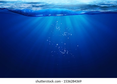 Deep Blue Sea Under Water Light Ray Through On Wavy Sea Surface  And Small Bubbles Under The Ocean Summber Concept Background