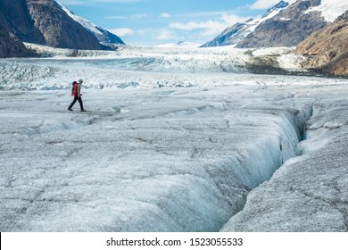 Deep in the Boundary Mountain Range between Alaska and Canada, an ice climber walks across the massive Salmon Glacier.