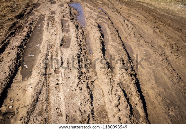 Deep car rut on a dirt road. Empty countryside dirt\
wet road.