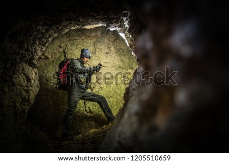 Deep Cave Exploration by Men with Flashlights and Backpack. Caucasian Caver in the Grotto.