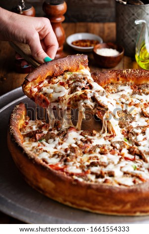 Deep dish meat pizza on a wooden table with a slice being pulled Stock photo © 