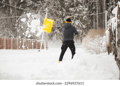 Deep drifts of snow after a heavy storm - an adult man clears the paths from snow with a shovel - digging a car out of a snowdrift