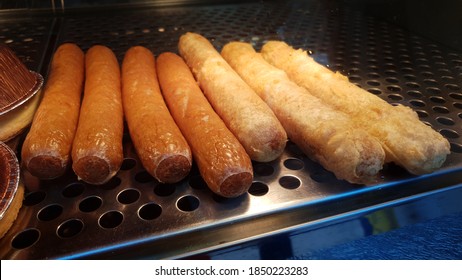 Deep fried battered sausages keeping warm on a hot plate in a fish and chip shop