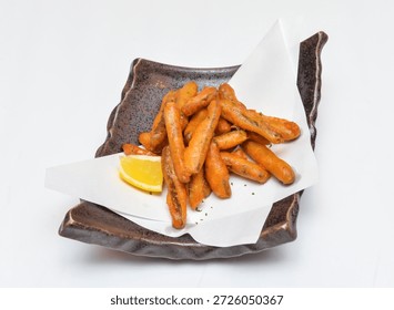 Deep fried burdock root or Crispy fried baby carrots served on a rustic plate with a slice of lemon, perfect for a healthy and tasty snack or appetizer
