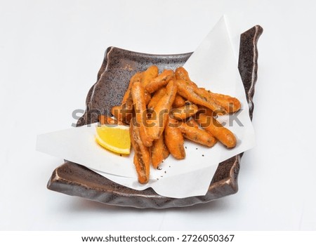 Deep fried burdock root or Crispy fried baby carrots served on a rustic plate with a slice of lemon, perfect for a healthy and tasty snack or appetizer