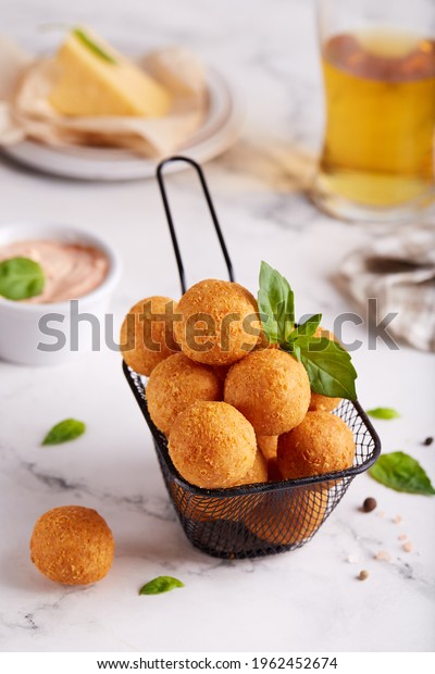 Deep fried\
Cheese balls. Delicious homemade appetizer. Freshly baked\
croquettes, served with basil leafs and\
sauce.