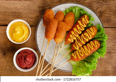 Deep fried corn dogs with mustard and ketchup on wooden background. American junk food concept. Top view - Powered by Shutterstock