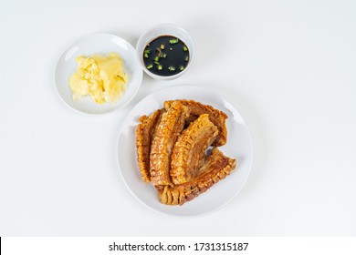Deep Fried Crispy Streaky Pork Belly Thai and Chinese Food on White Plate with Sauce and Ginger on Isolated Background.