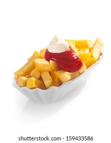 Deep Fried Golden Potato Chips Or Wedges Served With A Dollop Of Ketchup And Mayonnaise On Top In A Fluted Container Over A White Background