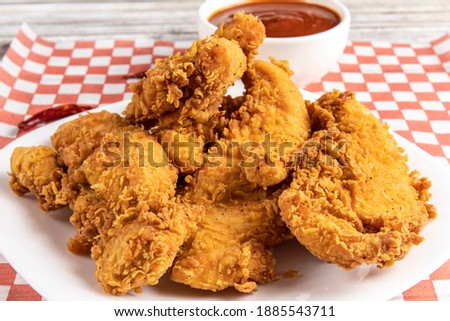 deep fried southern style breaded chicken tenders or chicken fingers on a white plate with dipping sauce