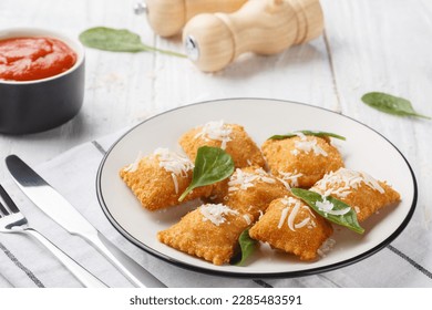 Deep fried traditional italian dish ravioli dumplings stuffed with spinach and cheese served with marinara tomato dipping sauce closeup on the wooden table. Horizontal
 - Powered by Shutterstock