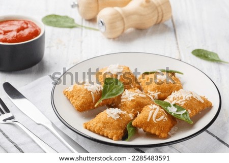 Deep fried traditional italian dish ravioli dumplings stuffed with spinach and cheese served with marinara tomato dipping sauce closeup on the wooden table. Horizontal
