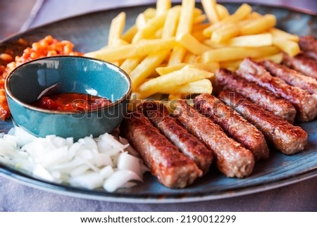 Deep fried traditional rolled Cevapcici, ground meat patties with French fries and ketchup served at restaurant. Specific Balkans countries food in Porec, Croatia.