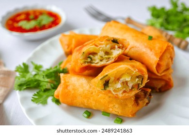 Deep fried vegetable spring rolls or egg rolls and sauce , Thai called popia, in white plate on a white table background with fork, close up