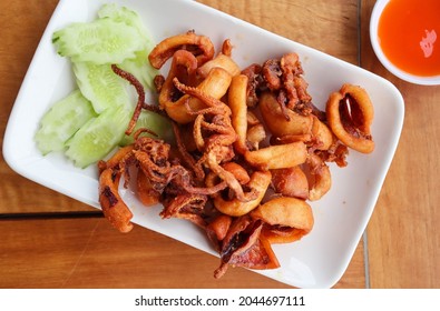 Deep fry sun-dried squid in white plate of wood table - Seafood at top view
