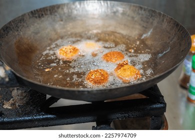 Deep frying falafel balls in a wok, hot cooking oils bubbling, and falafel balls turned a golden brown color - Shutterstock ID 2257974709