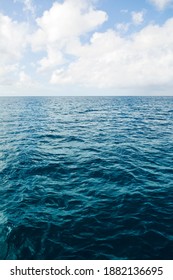 Deep ocean view with waves and white clouds. Relaxing seascape, endless sea, tropical waters background. Blue seas and skies separated by a far away horizon. Caribbean lifestyle themes.
