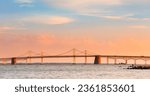 deep orange and blue sunset over chesapeake bay with golden bridge lit up by sun - water reflecting sky colors with chesapeake bay bridge
