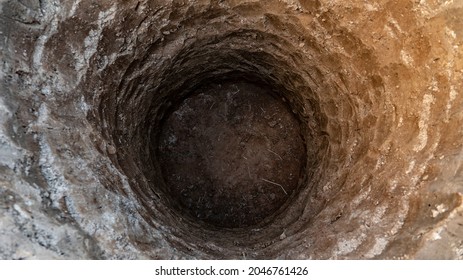 Deep pit in the ground. Digging a hole. Water Well Drilling, Dig a well for water, Groundwater hole drilling machine. Big bottomless hole in the ground - Shutterstock ID 2046761426
