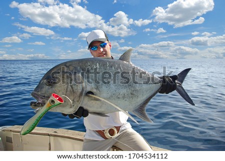 Deep sea fishing, popping. Man holding a Trevally jack fish