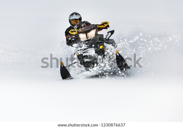 In deep snowdrift snowmobile rider make fast\
turn. Riding with fun in deep snow powder during backcountry tour.\
Extreme sport adventure, outdoor activity during winter holiday on\
ski mountain resort.
