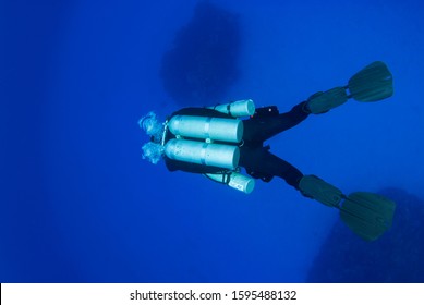 A Deep Technical Diver Has A Set Of Doubles Or Twin Set On His Back In Addition To Two Stage Tanks On The Side. The Diver Is Prepared To Do A Deep Tech Dive Involving Planned Decompression