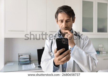 Deep thinking and smart device. Thoughtful contemplative male doctor medical professional concentrated on cellphone screen analyze patient lab test data via text message to make diagnosis. Copy space