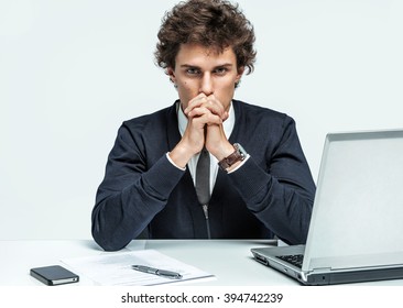 Deep in thought man. Businessman at the workplace working with computer on gray background.