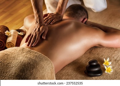 Deep tissue massage. Spa setup - stones, frangipani flowers and towels.
