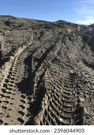 deep tracks of tractors and excavators in the mud after the flood, large tire tracks in the sand and mud