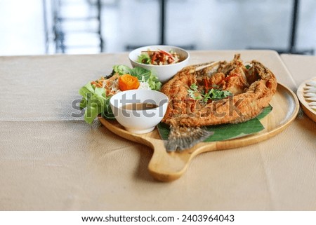 Deep-fried sea bass with fish sauce is popular dish. Deepfried sea bass with fish sauce served with mellow dipping sauce with sliced ​​mango to add flavor and fresh vegetables arranged in wooden plate
