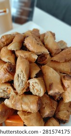 ​Crispy deep-fried spring rolls filled with mixed vegetables and vermicelli, sliced into bite-sized pieces and served on a white plate.