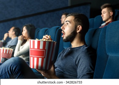 Deeply entertained. Horizontal portrait of a young man watching movie attentively with his mouth open