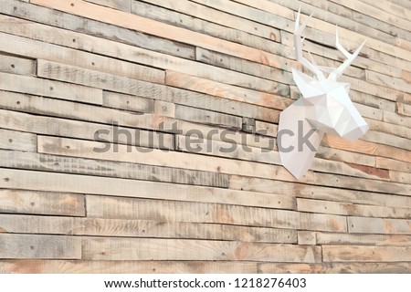 Deer head made of paper on a wall of wooden slats. View at an angle. Designer background for decoration in the room. Christmas wall decoration. Copyspace.
