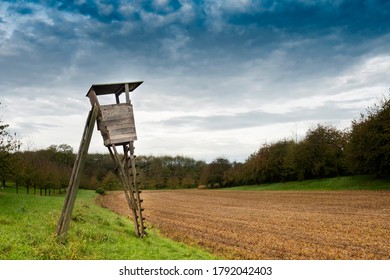 Deer Stand Hunting Tower Next To A Field, Dark Overcast Sky. 