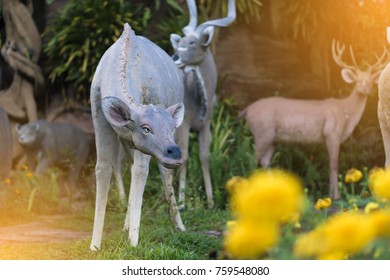 deers statue on nature background , yellow flowers foreground. 