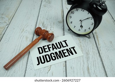 Default Judgment text on paper card with alarm clock and wooden judge gavel top view on wooden background