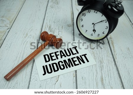 Default Judgment text on paper card with alarm clock and wooden judge gavel top view on wooden background