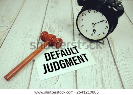 Default Judgment text on paper card with alarm clock and wooden judge gavel top view on wooden background