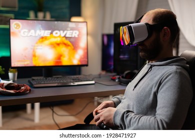 Defeated Gamer Man Losing Video Game Tournament Playing With Virtual Reality Headset. Competitive Player Using Joystick For Online Competition Late At Night In Gaming Room